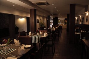Un restaurant où les tables sont dressées pour le service, offrant une variété d’aménagements et un décor intérieur moderne.