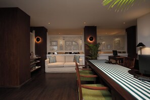 A modern living room with a sofa, a dining table with chairs, and a TV. - Hotel Casamara (Kandy)