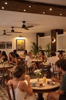 A restaurant with round tables, ceiling fans, and wall-mounted artwork.