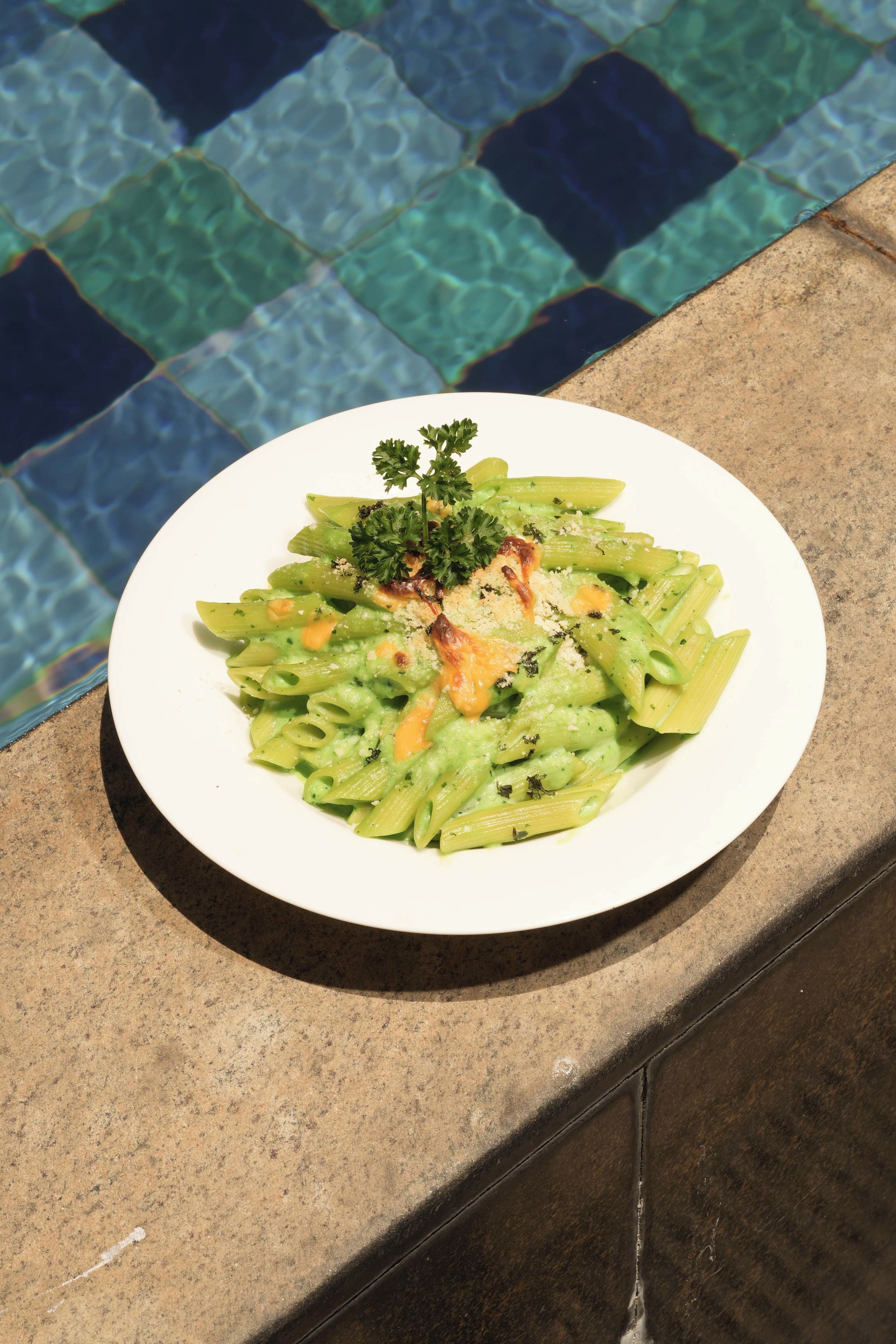 Un plato de pasta con adornos sobre una mesa junto a una piscina.