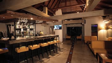 A bar area with a high ceiling, wooden beams, and a bar counter with stools.