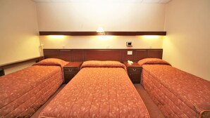 A hotel room with three beds, a wooden headboard, bedside lamps, and a small table with a phone. - Bristol (Gibraltar)