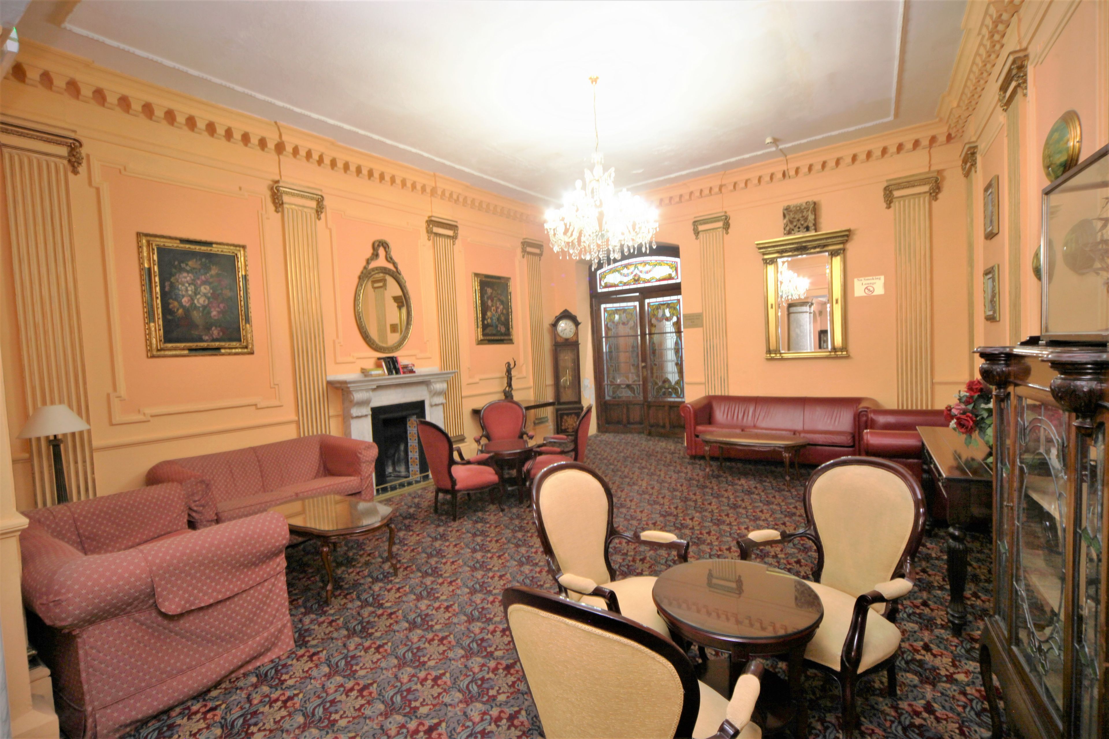 A room with a fireplace, red sofas, a chandelier, and a mirror.