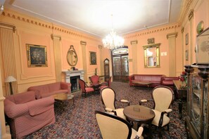 A room with a fireplace, red sofas, a chandelier, and a mirror. - Bristol (Gibraltar)