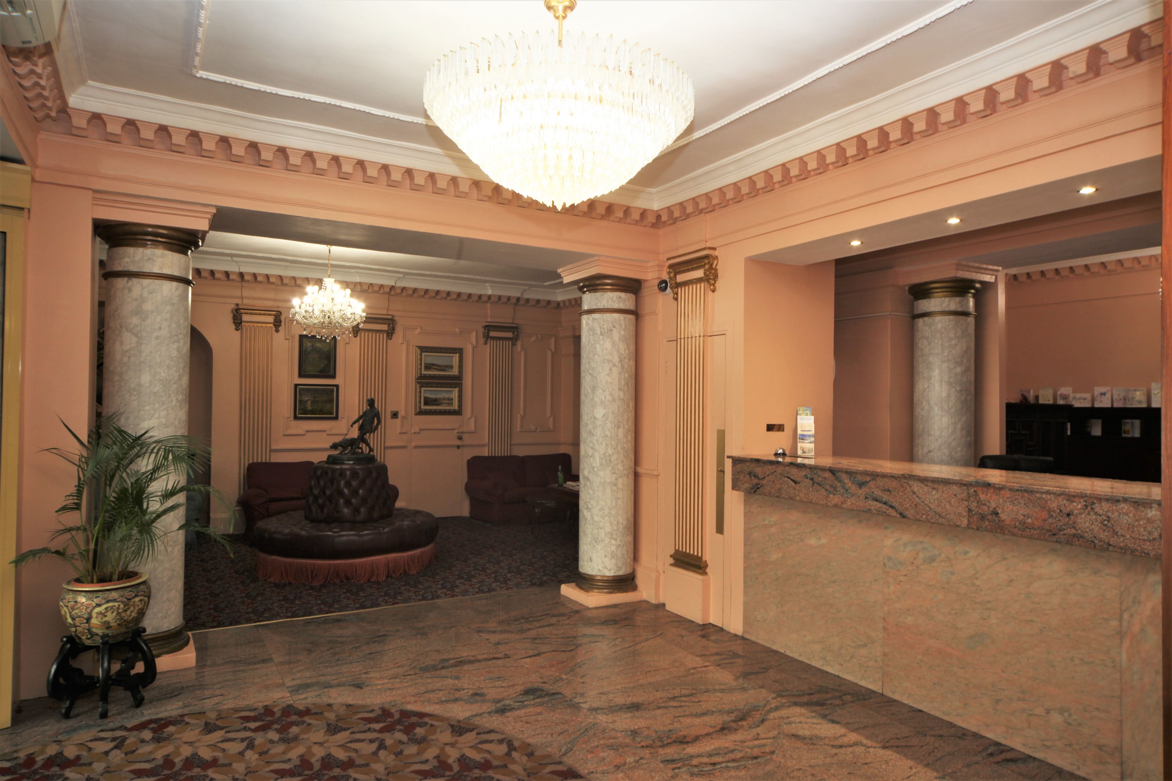 A lobby with a marble floor, a grand chandelier, and a reception desk.