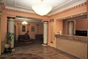 A lobby with a marble floor, a grand chandelier, and a reception desk. - Bristol (Gibraltar)
