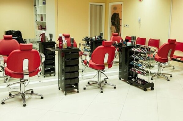 Un salón con sillas rojas, un espejo y estantes con productos para el cabello.