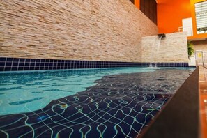 Una piscina con pared texturizada y borde de azulejos.