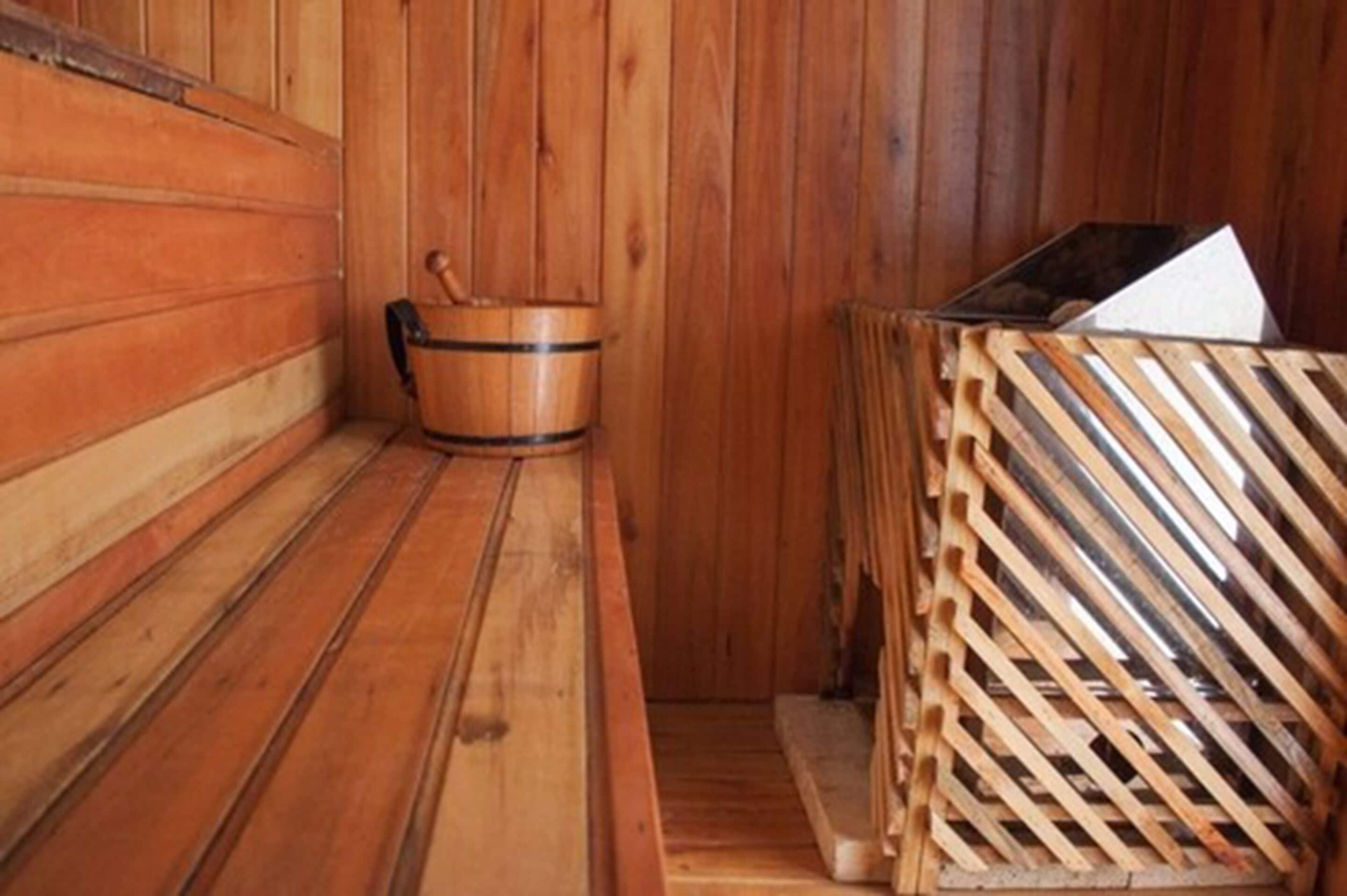 A wooden sauna with benches and a wooden bucket.