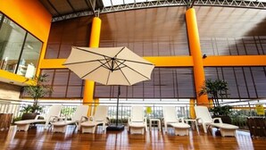 Amplio espacio interior con suelo de madera, sillones blancos y un parasol colgante.