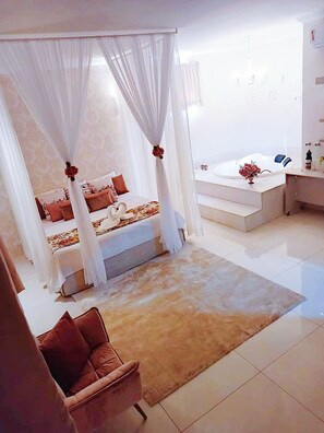 A bedroom with a canopy bed, a sitting area with a chair, and a bathroom with a bathtub. - Hotel Pousada Chalé Das Flores (Sertaozinho)