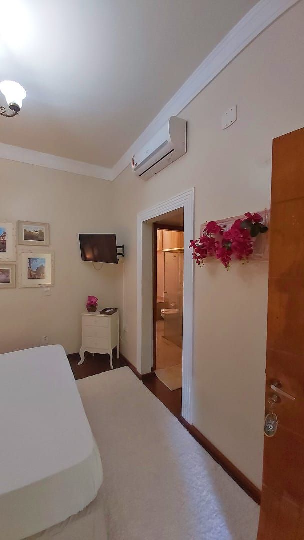 Un dormitorio con una cama, televisión, mesita de noche y una puerta que da al baño.