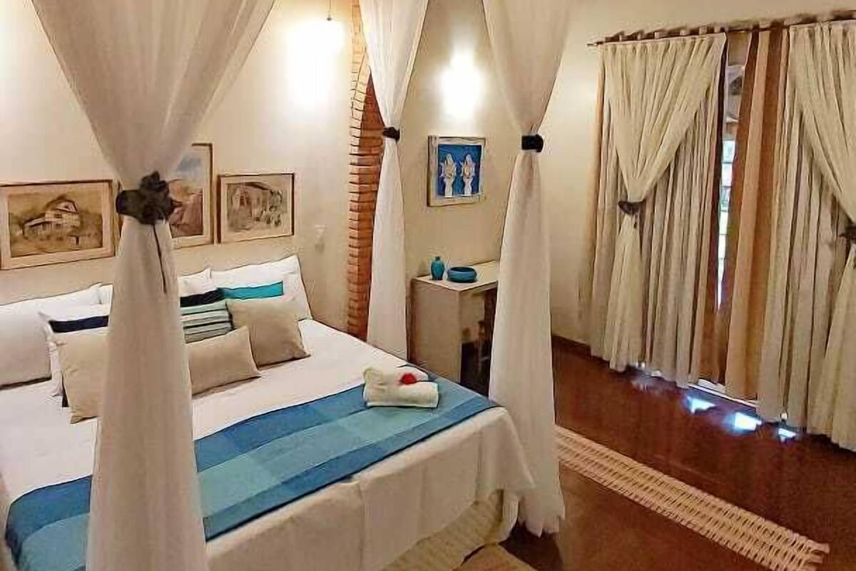 Un dormitorio con una cama grande, cortinas blancas y techo de madera.