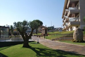 Un barrio residencial con un árbol grande, una escultura de piedra y edificios de apartamentos modernos.