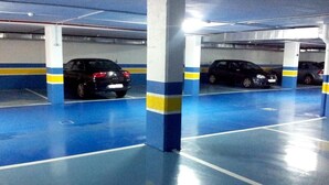 Eine mehrgeschossige Tiefgarage mit blau und gelb gestrichenen Säulen und einem sauberen, spiegelnden Boden.