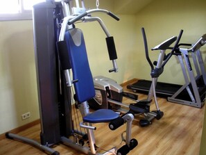 Un gimnasio en casa con una bicicleta estática, una máquina de pesas y una cinta de correr.