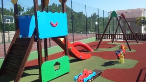 Ein Spielplatz mit Klettergerüst, Rutschen und Schaukeln.