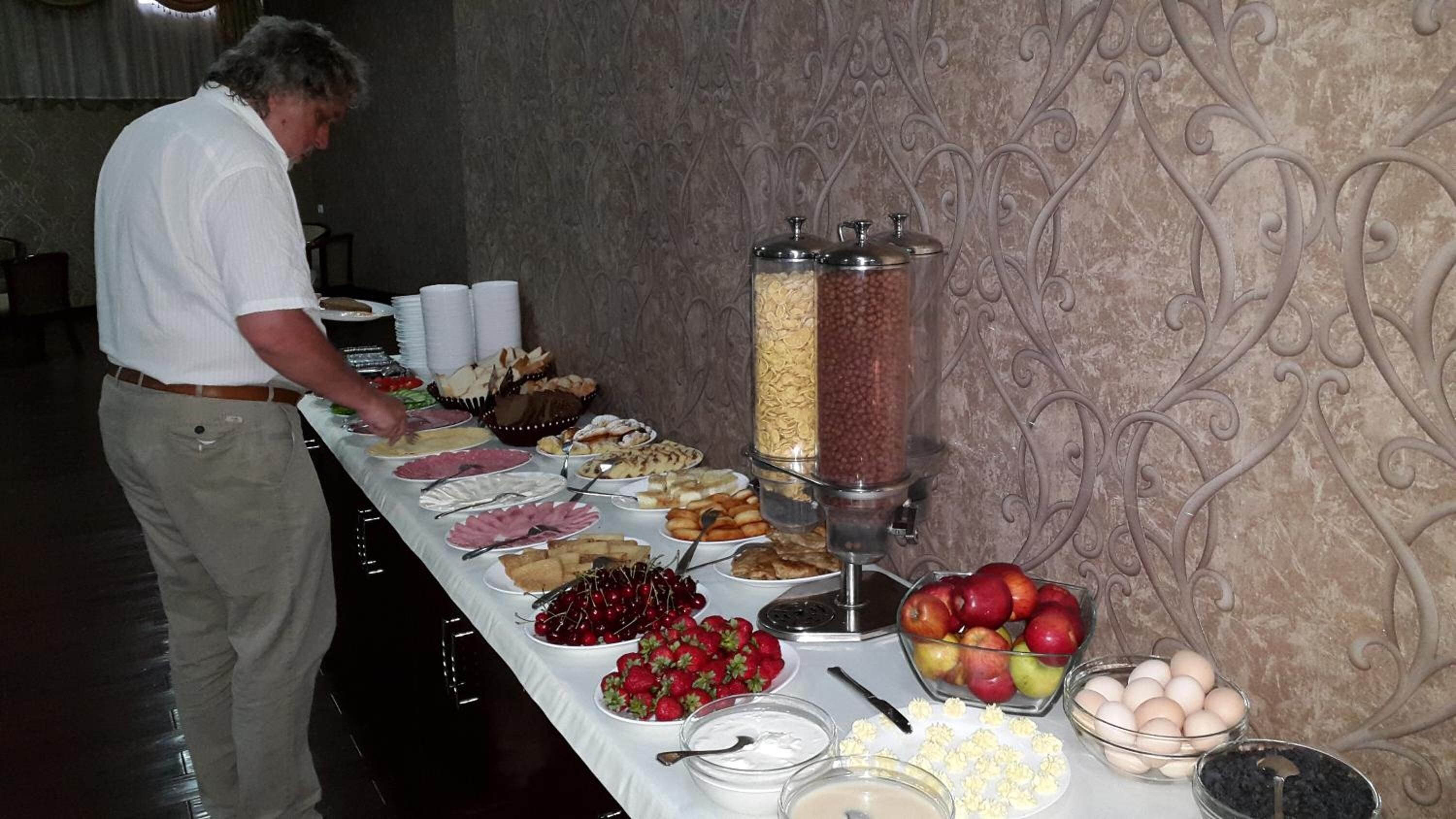 Una mesa de bufé con diferentes alimentos y una persona sirviendo.