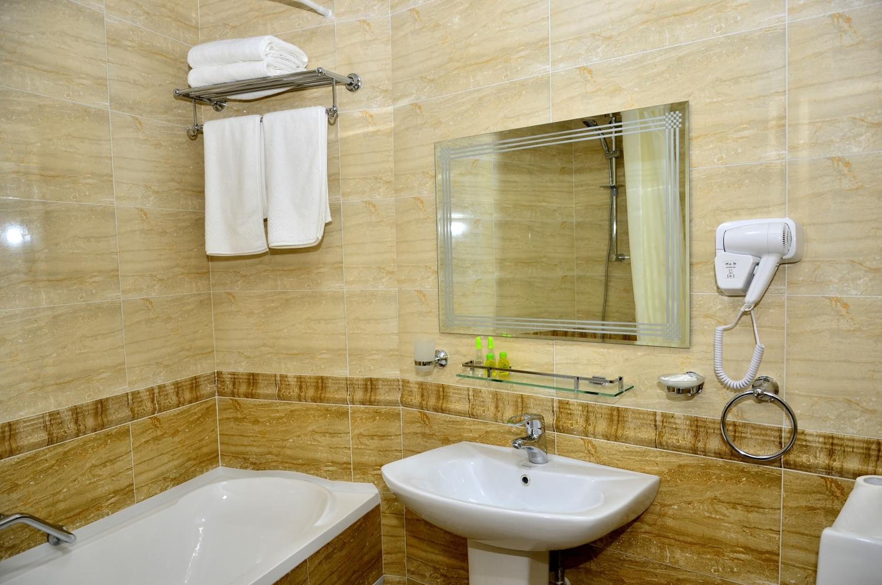 A bathroom with a bathtub, sink, and a glass shower enclosure. There are towels and toiletries on the wall.