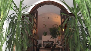 A room with a wooden archway, potted plants, and a mirror reflecting the room's interior. - Hotel Doxa (Agios Nikolaos)