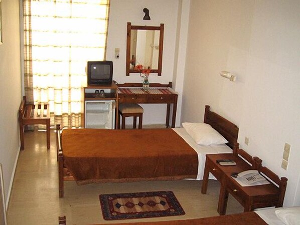 A bedroom with a bed, a desk, a chair, a television, and a window with curtains. - Hotel Doxa (Agios Nikolaos)