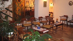A dining area with wooden chairs and tables, a decorative wall with plants, and wall-mounted lights. - Hotel Doxa (Agios Nikolaos)