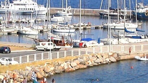 A marina with boats docked and people swimming in the water. - Hotel Doxa (Agios Nikolaos)