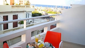A balcony with a table set for breakfast, overlooking a marina with boats. - Hotel Doxa (Agios Nikolaos)