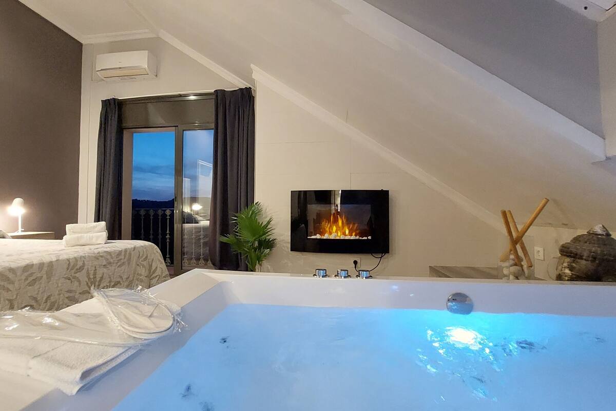 Een moderne slaapkamer met een groot bed, een badkuip en een aan de muur bevestigde televisie.