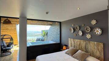 A modern bedroom with a large bed, a view of the outdoors, and decorative wall art.