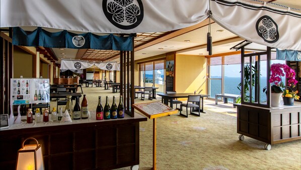 Un restaurante con vistas al mar, que cuenta con una pizarra de menú, botellas de vino y un arreglo floral.