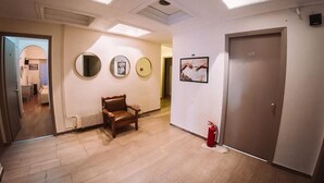 Un pasillo con un sillón de cuero marrón, un extintor y una puerta con la etiqueta '105'.