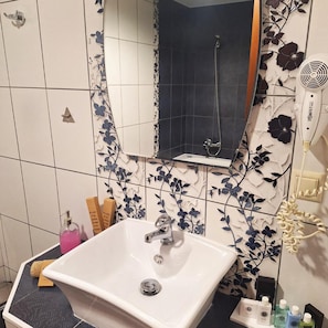 A bathroom with a white sink, a mirror, and a shower.