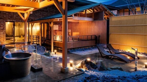 A modern outdoor patio with a fire pit, lounge chairs, and a wooden pergola. - Saiou No Miya (Ise)