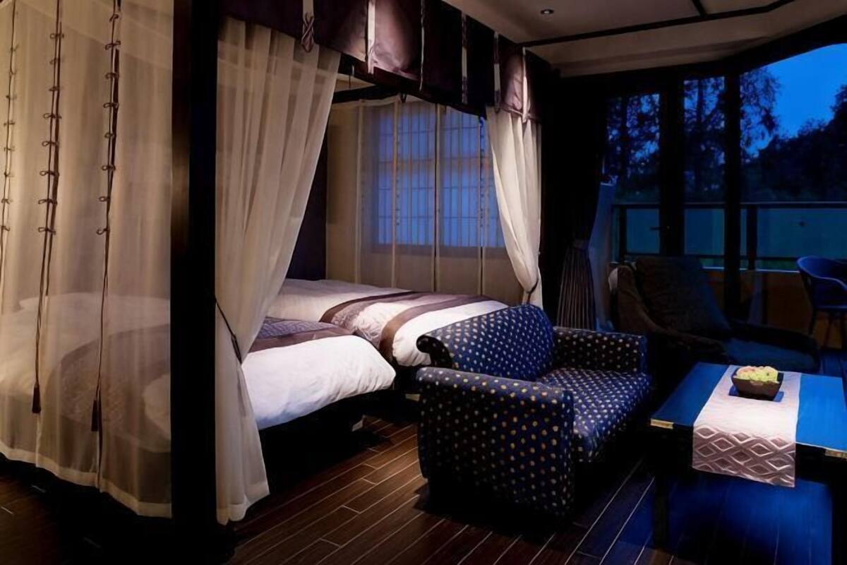 Ein Schlafzimmer mit Bett, Stuhl, Tisch und Fenster.