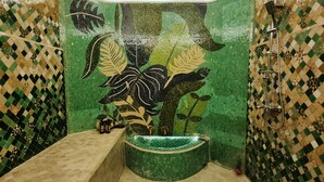 Une salle de bain avec un mur recouvert de mosaïques vertes, une baignoire et un espace douche.