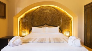 Une chambre d’hôtel avec un grand lit, une tête de lit décorée et deux lampes de chevet.