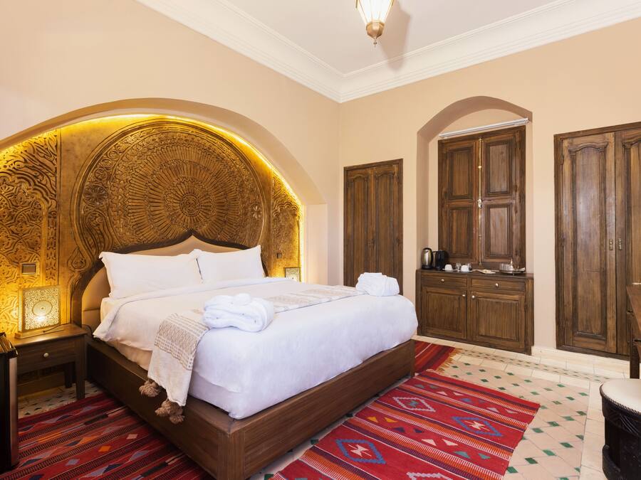 Un dormitorio amplio con una cama grande, armario de madera y un cabecero decorativo.