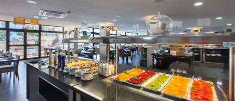 A buffet area with various food options and a seating area in the background.