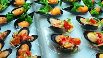 En buffetbod med forskellige fiskeanretninger, herunder rejer, muslinger og laks, anrettet i glas.