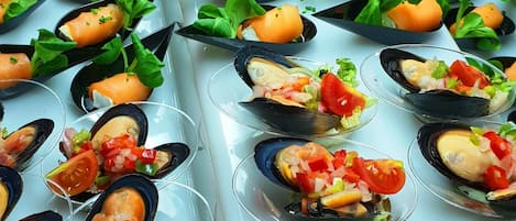 A buffet table with various seafood dishes, including shrimp, mussels, and salmon, arranged in clear glasses.