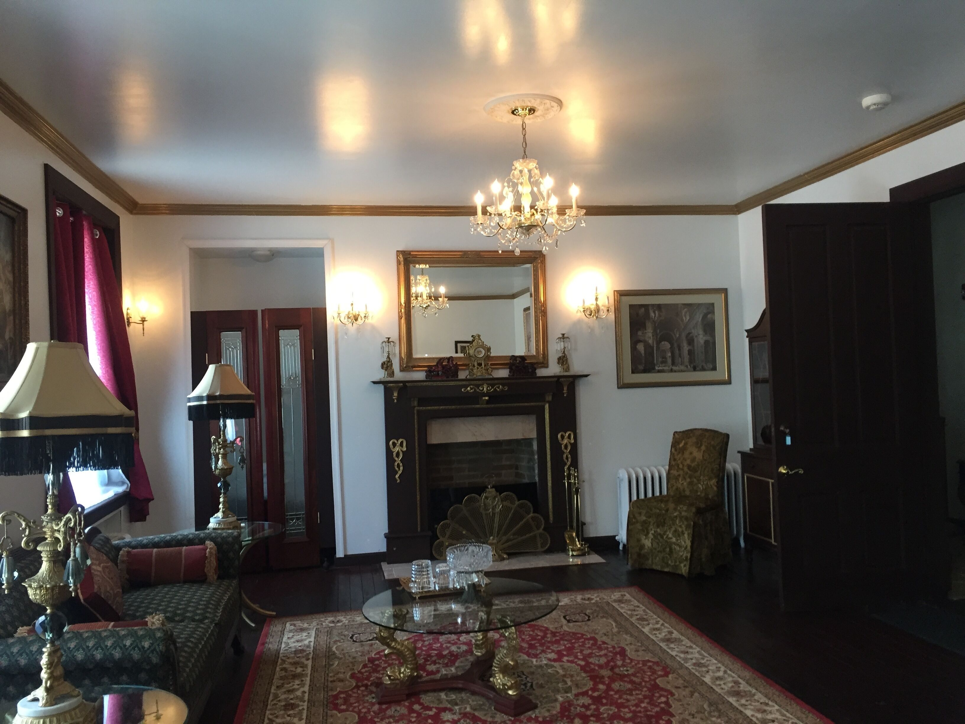 A traditional living room with a fireplace, a chandelier, and a large mirror.