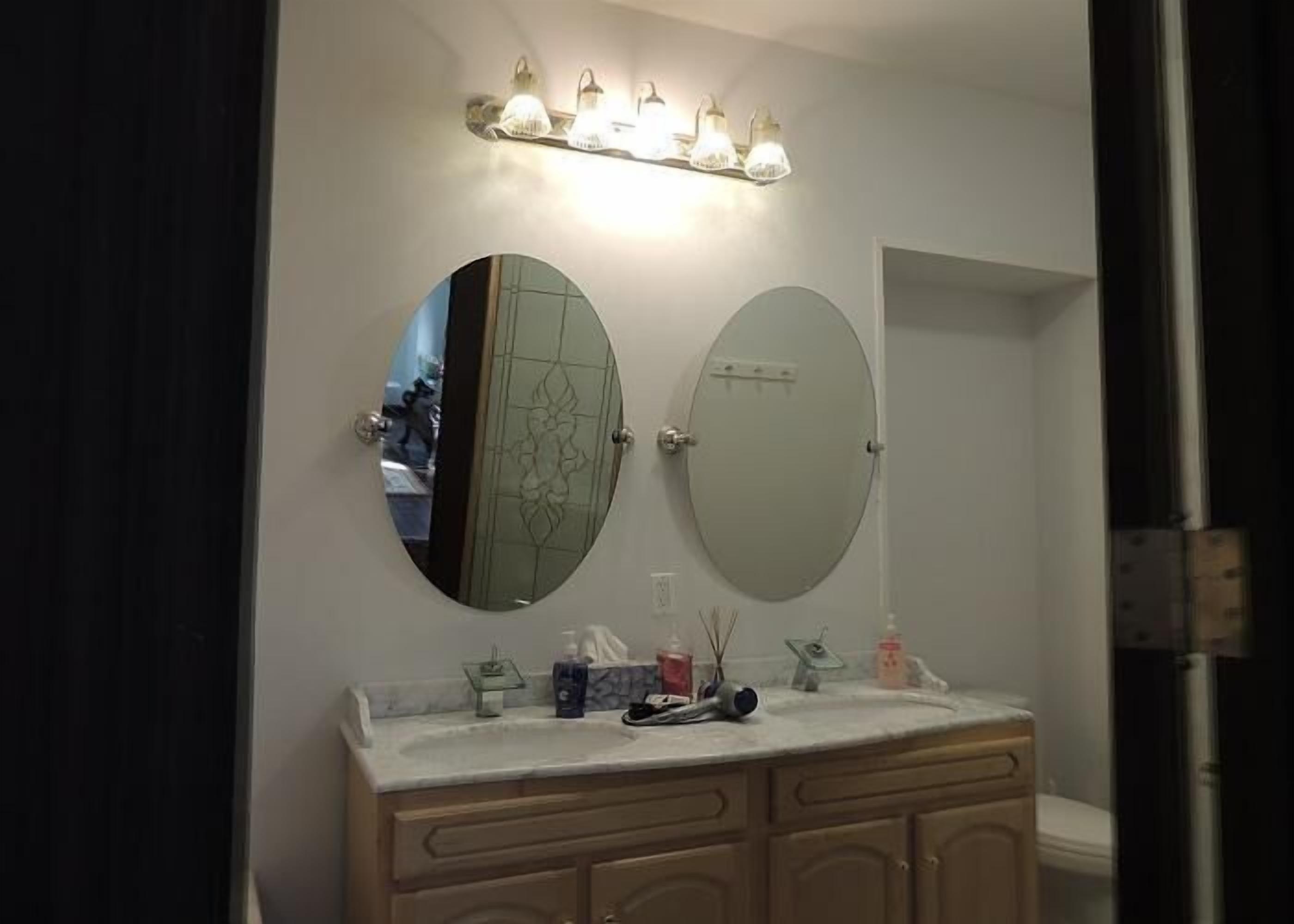 A bathroom with a double vanity, a large mirror, and a light fixture above the mirror.