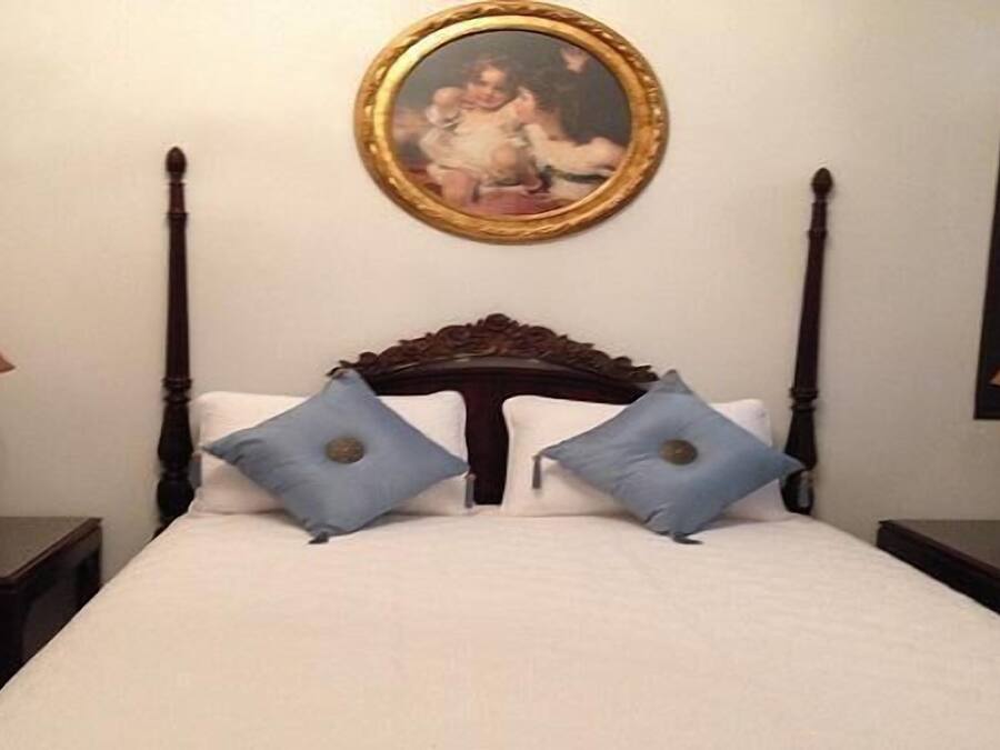 Una camera d'albergo con un letto grande, due comodini, due lampade e un quadro incorniciato al muro.