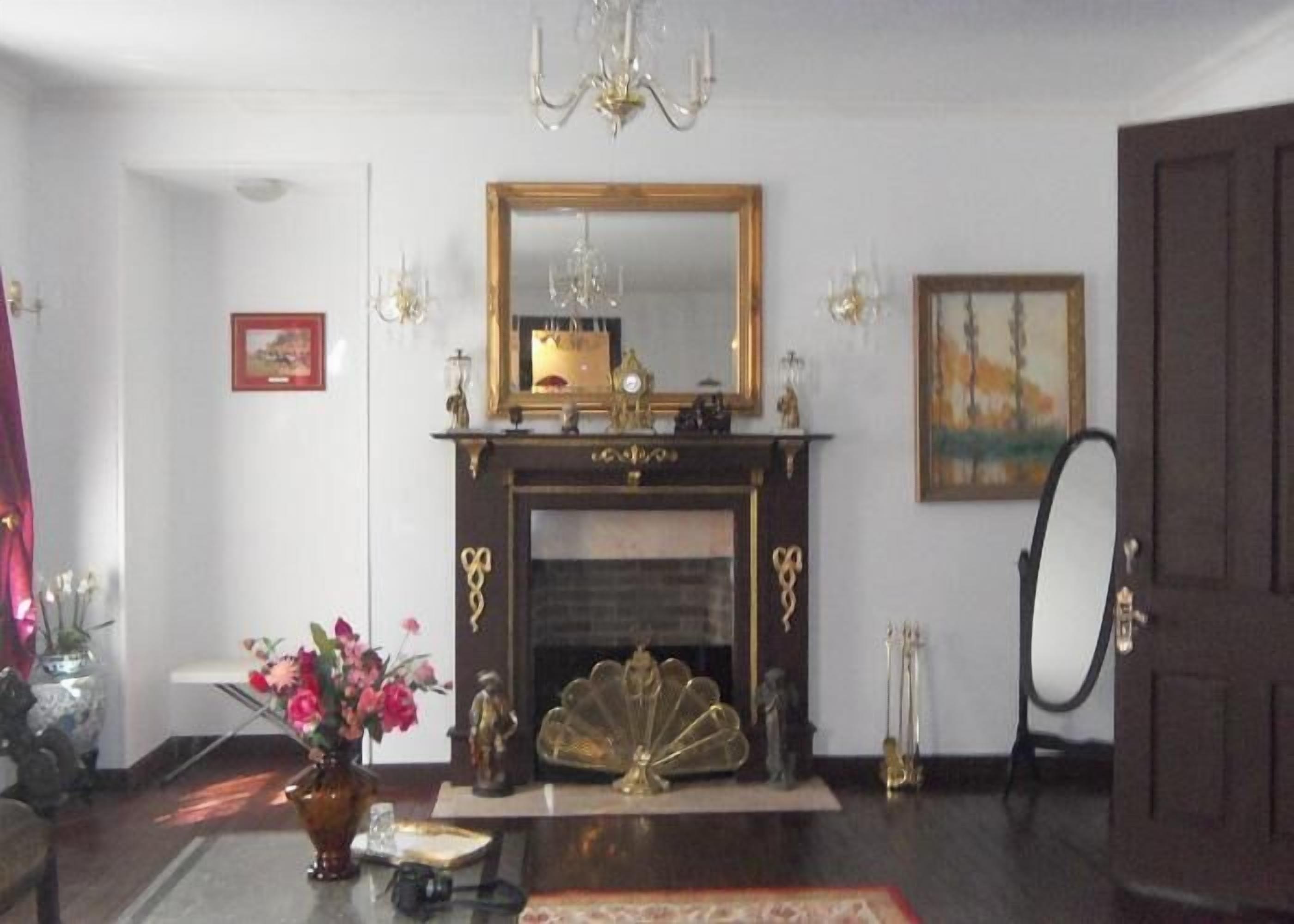 A room with a fireplace, a mirror, and a chandelier.
