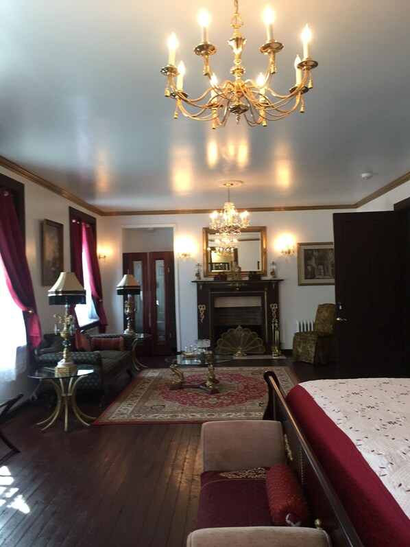 A room with a chandelier, a fireplace, a sofa, a table, and a bed. - Thornwald Mansion (Carlisle)