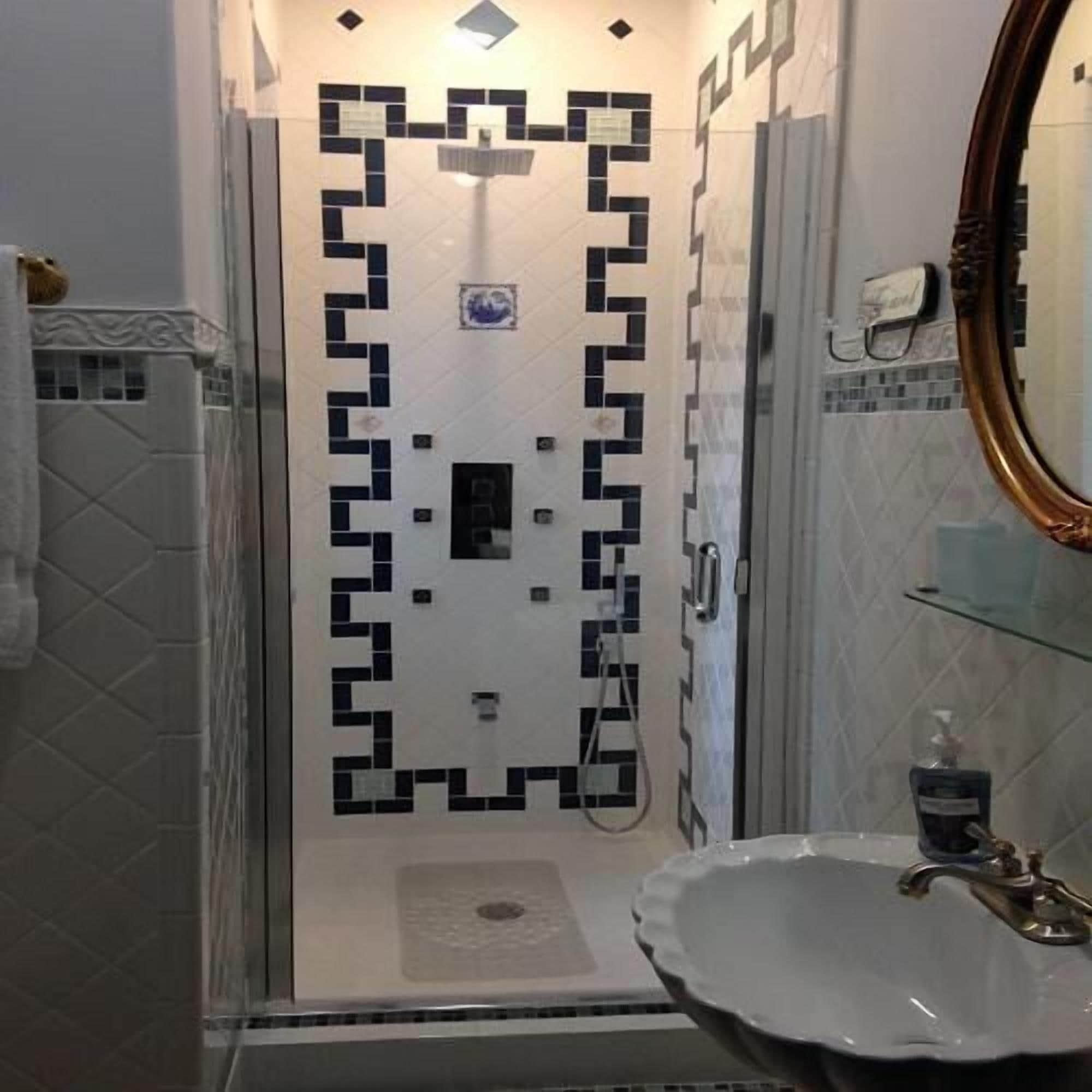 A bathroom with a white sink, a mirror, and a shower area.