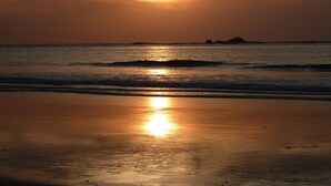 Una playa al atardecer con olas tranquilas y cielo despejado.