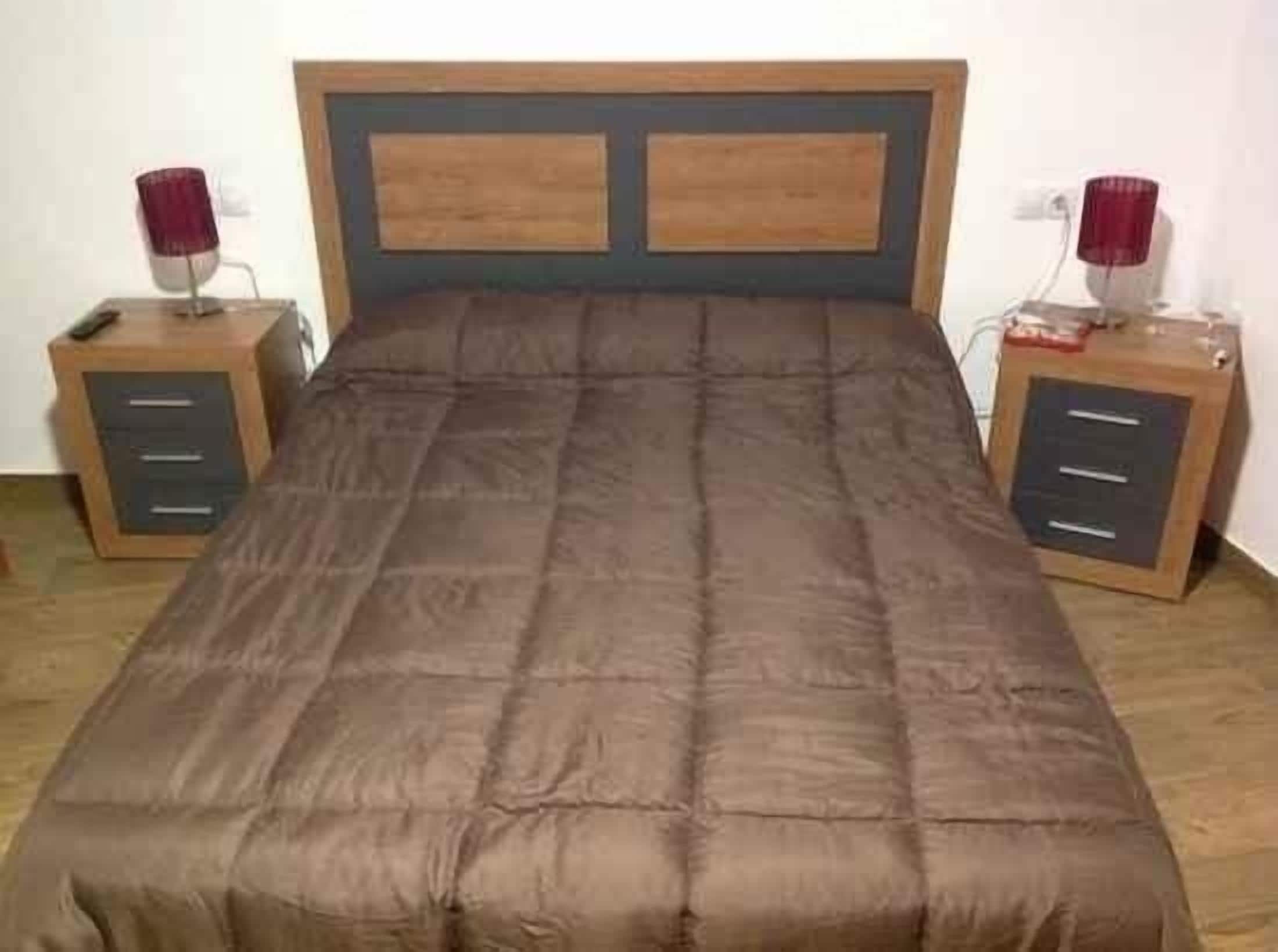 A bed with a wooden headboard and two nightstands with drawers.