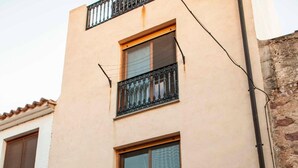 A multi-story building with a beige facade, a wooden door, and barred windows.
